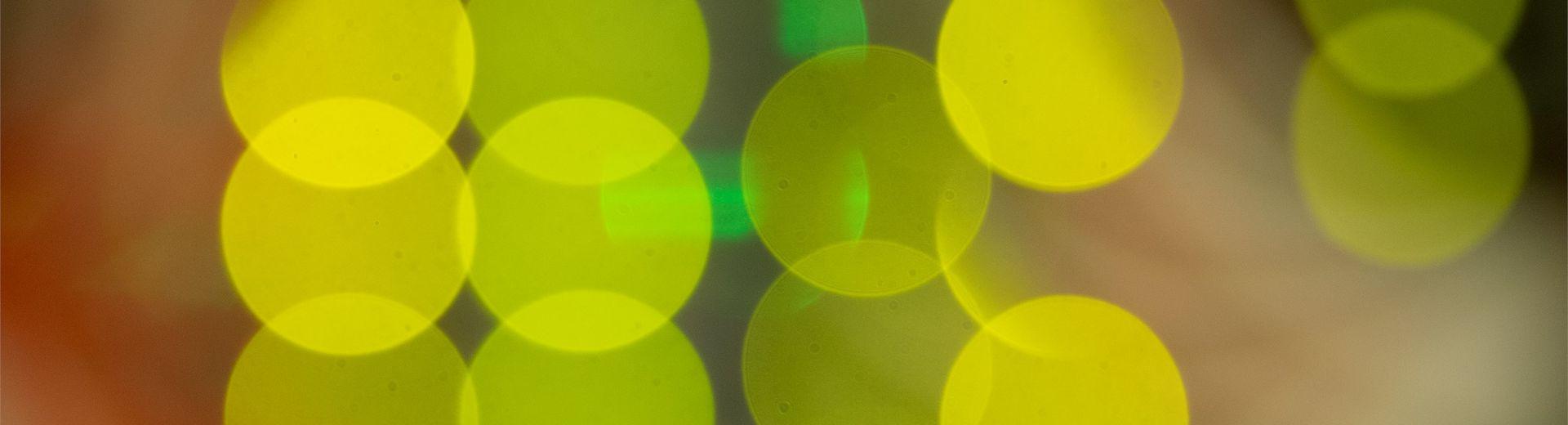 Image is a super close up shot of lights in 的 back of computer servers resulting in an image of overlapping bright yellow discs of color.